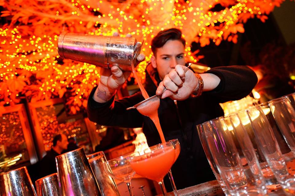 Cocktail waiter in lit-up bar venue
