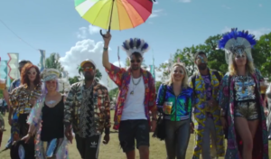 Group of party-going people dressed up and carrying Pride umbrella at festival