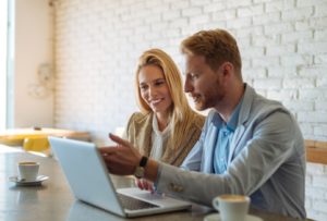 Couple in their thirties having coffee and looking at laptop together